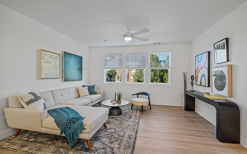 Pet-Friendly Townhomes in Vacaville, CA - The Preserve at Harbison - Furnished Living Room with Wood-Style Flooring, Ceiling Fan, and Three Windows