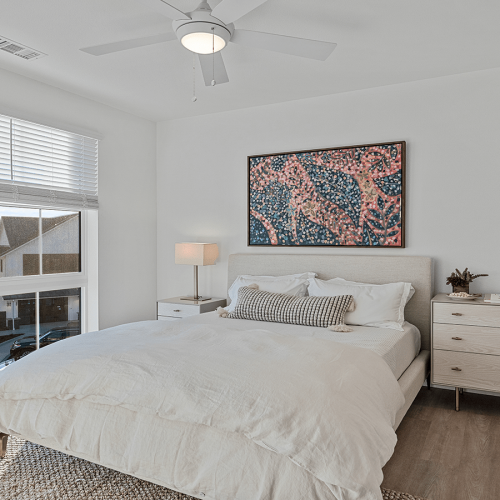 Vacaville CA Apartments - The Preserve at Harbison - Well Lit Bedroom with Oversized Windows, En Suite Bathroom, Wood Plank Flooring, and Queen Bed